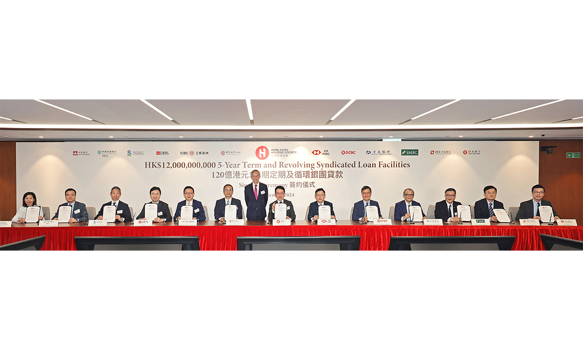 房協120億港元五年期定期及循環銀團貸款的簽約儀式日前於房協企業辦事處舉行，由房協主席陳家樂（站立）擔任簽約儀式見證人，並由房協行政總裁陳欽勉（右七）代表房協簽署。